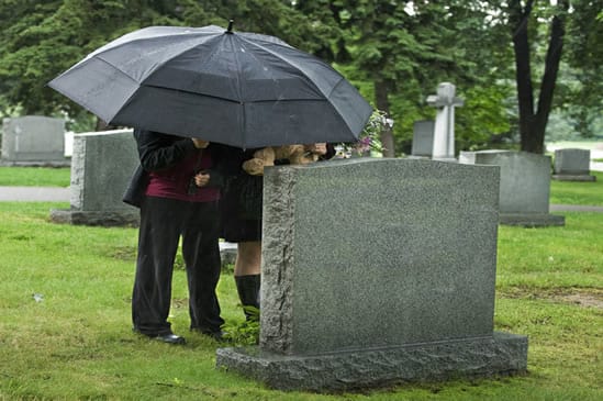 Family under umbrella at gravesite 