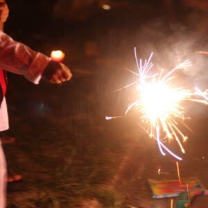 A person holding a sparkler at nighttime.