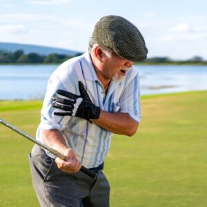 A person with a golf injury grasping their shoulder on the green.