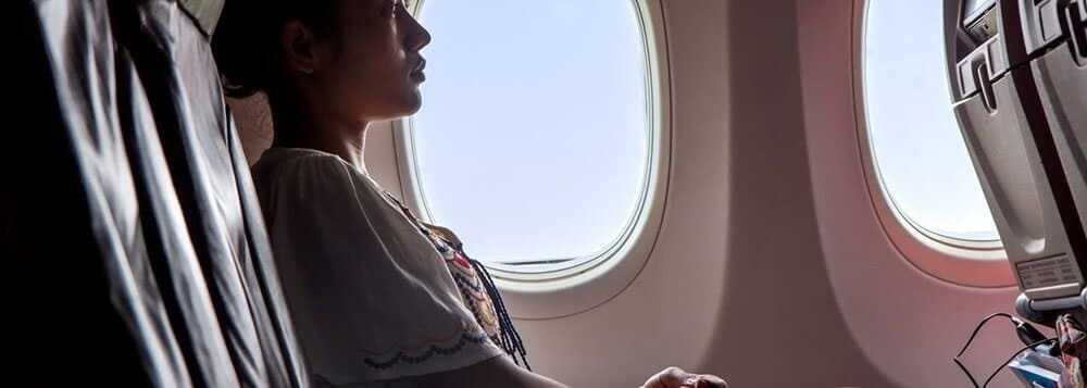 woman sitting alone in window seat in airplane
