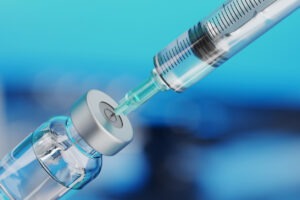 A vaccine syringe being filled with liquid from a vial.