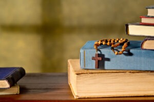 Biblical books stacked on one another with a rosary on top.