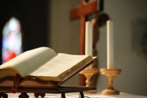A bible next to candles and a crucifix in a Catholic church.