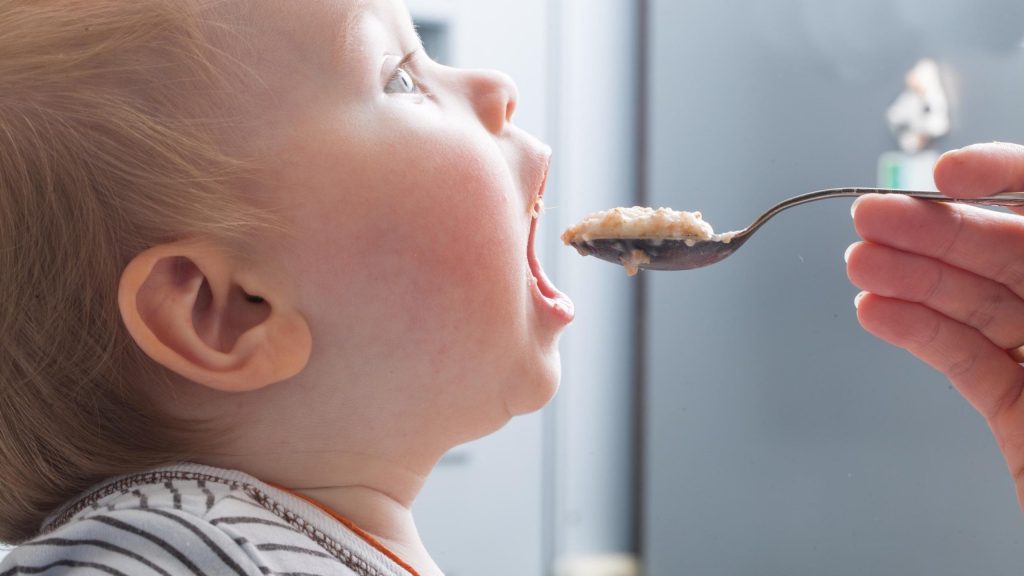 Baby eating food with mouth wide open