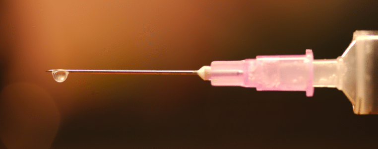 drop of vaccine on tip of metal of injection