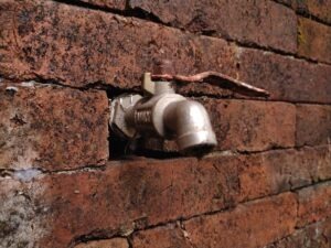 A water faucet attached to a brick wall.