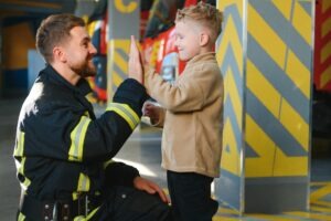 A firefighter high-fiving a child after teaching him about fire safety.