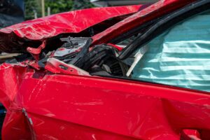 A closeup of a red car with its hood damaged from a car accident.