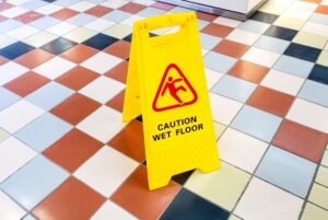 A checkered marble floor with a yellow sign that says "Caution: Wet Floor."