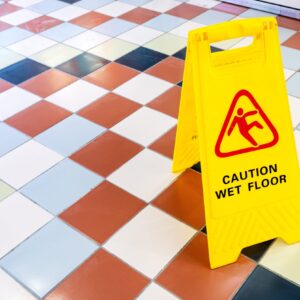 A checkered marble floor with a yellow sign that says "Caution: Wet Floor."