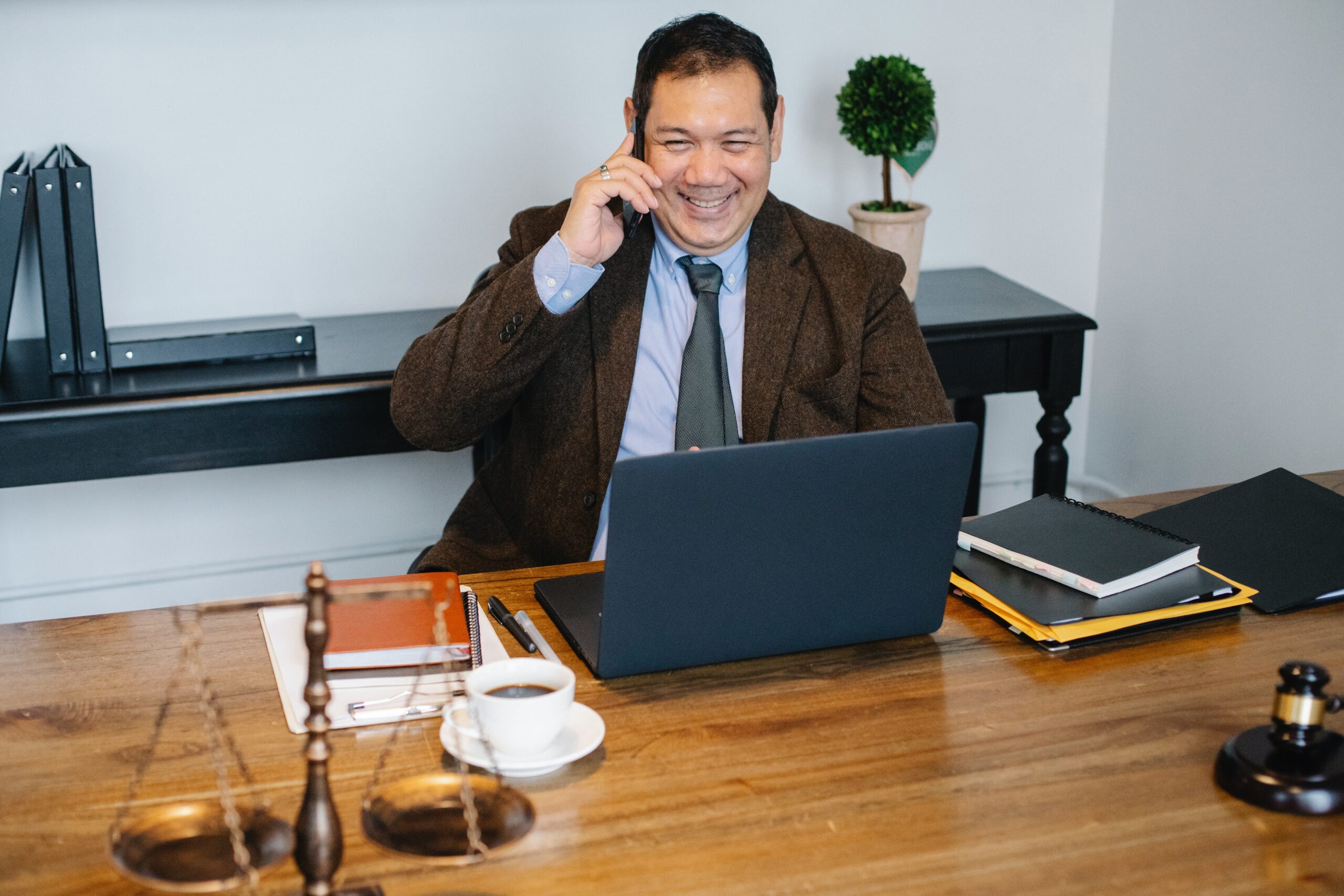 Man happily speaking on the phone in front of his laptop