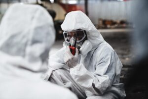 Two men in hazmat suits at a workplace with toxic chemicals.