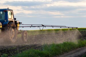 A tractor spraying pesticides on crops en mass.