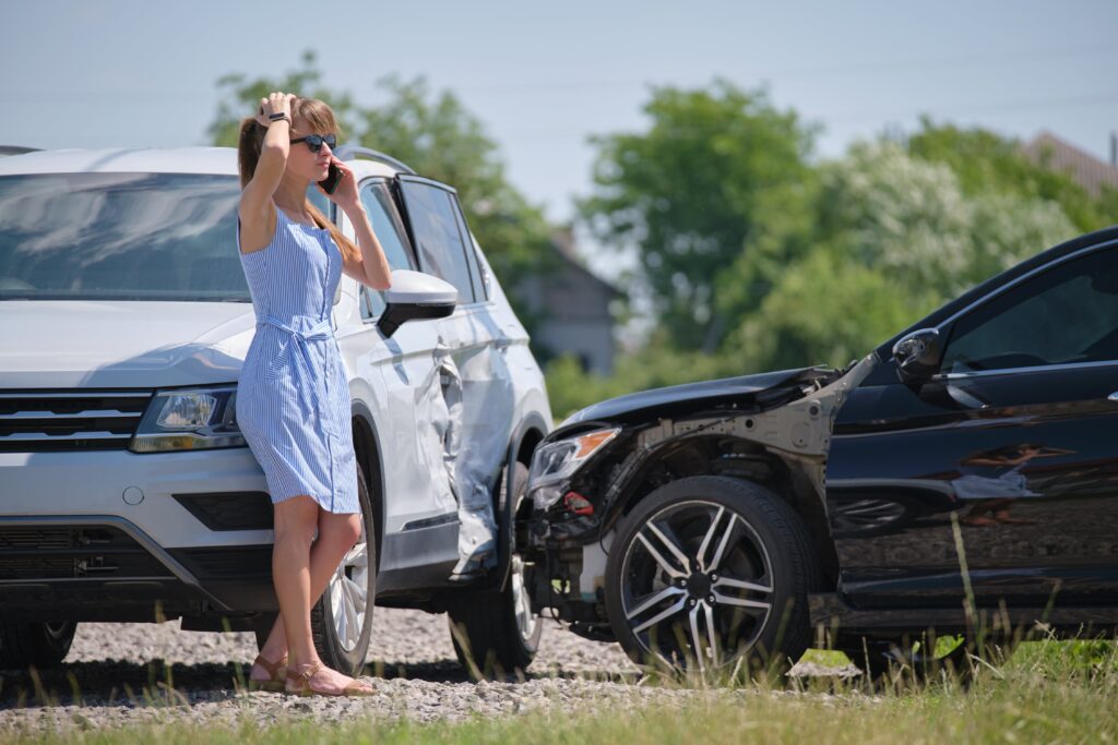 A stressed woman next to a motor vehicle accident.