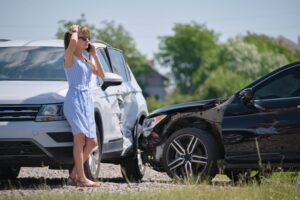 A stressed woman next to a motor vehicle accident.