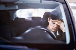 A driver stressed in his car following an accident while driving without insurance.