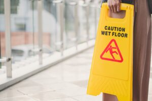 A woman holding a "Caution Wet Floor" sign.