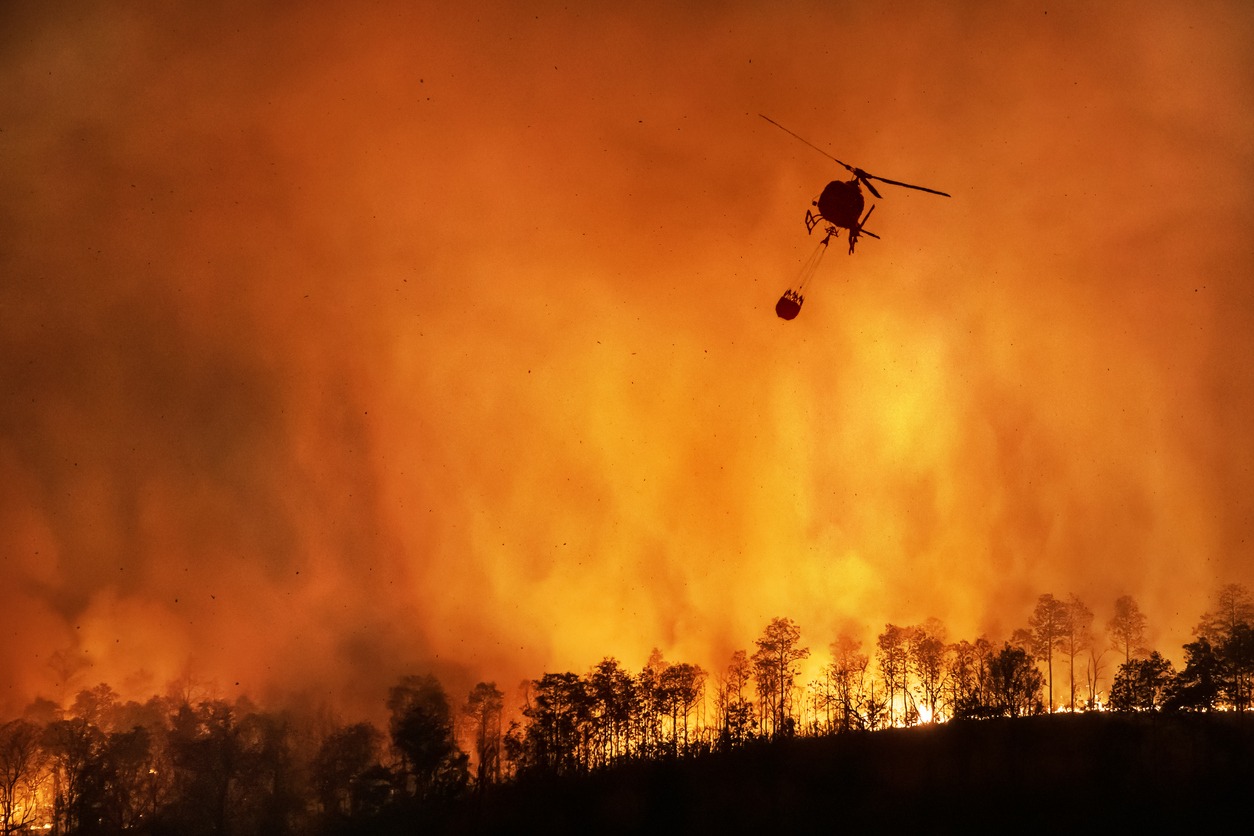 Helicopter carrying a bucket of water to help extinguish a wildfire.