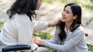 An elderly asian lady conversing with her daughter at a long term care facility.