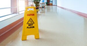A yellow sign that says "wet floor" atop a shiny, freshly mopped floor.