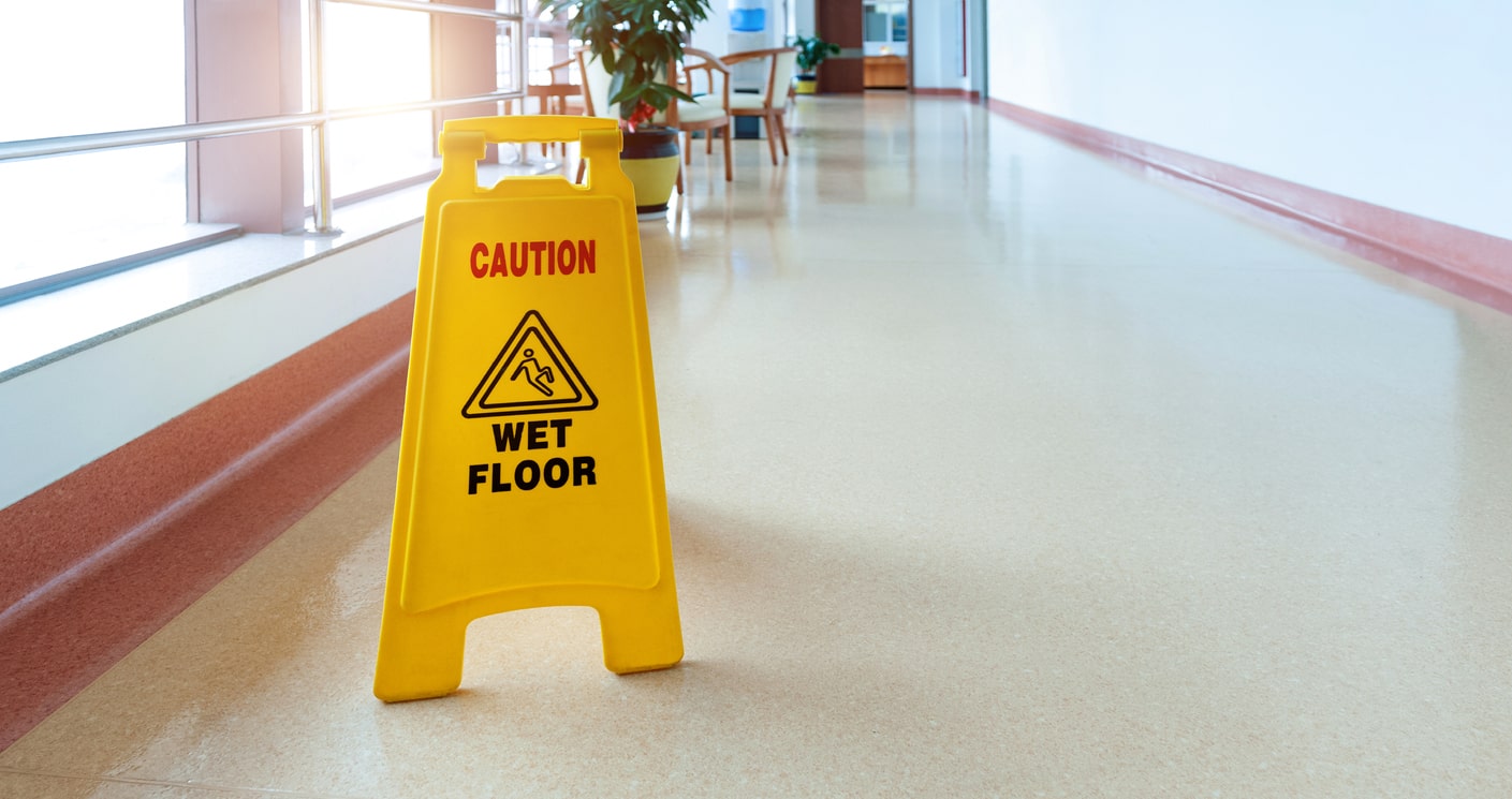 A yellow sign that says "wet floor" atop a shiny, freshly mopped floor.