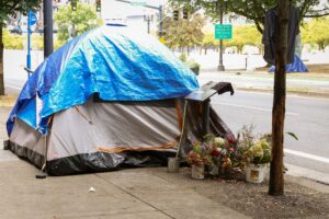 A tent in the middle of the sidewalk being used as shelter for a homeless person.