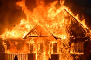 A house bursting with flames at night.