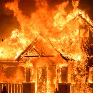 A house bursting with flames at night.