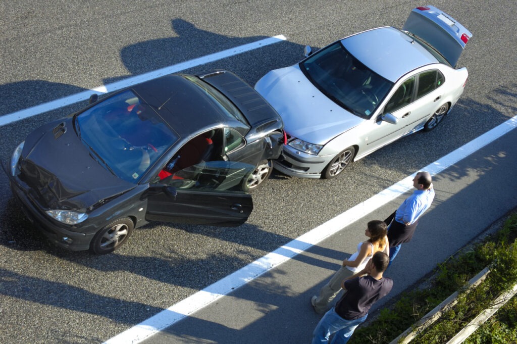 A Black car is rear-ended by a white car in the middle of the road.