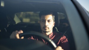 A man is driving his car carefully, pondering in his mind about when is the most dangerous time to drive every time he gets behind the wheel.