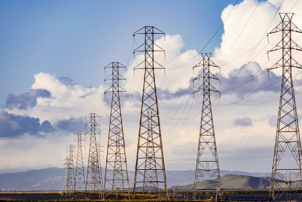 Several PG&E electrical power line towers standing next to one another on a sunny day.