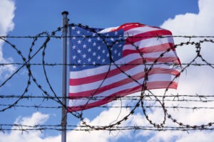 Barbed wire in front of the American flag to represent a ban.
