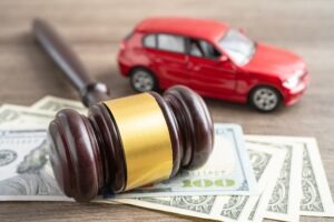 Gavel on money next to a toy car.