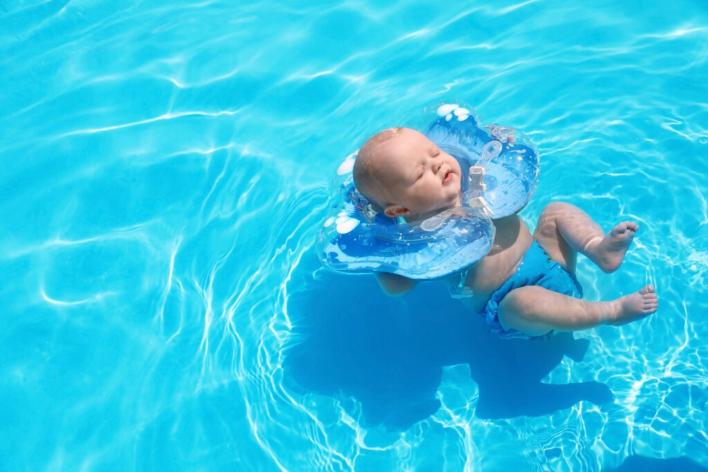 A baby floating in a pool using a neck floatie.