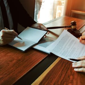 A lawyer looking at paperwork with their client over a desk.