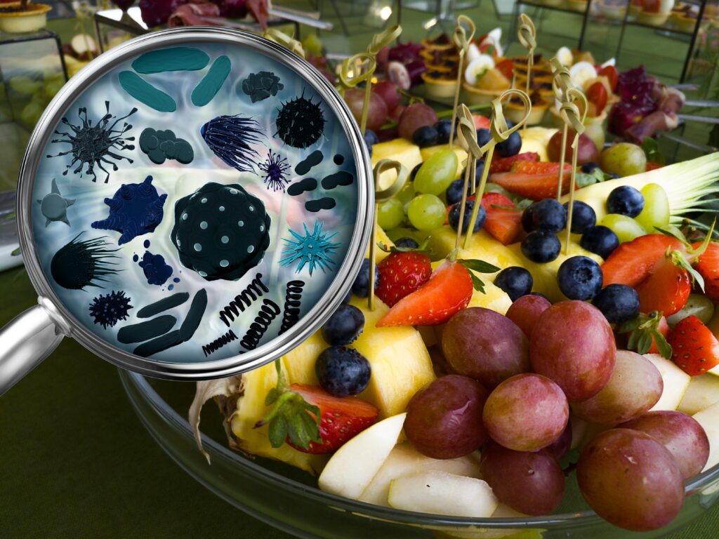 Magnifying glass revealing germs on fruits and veggies.