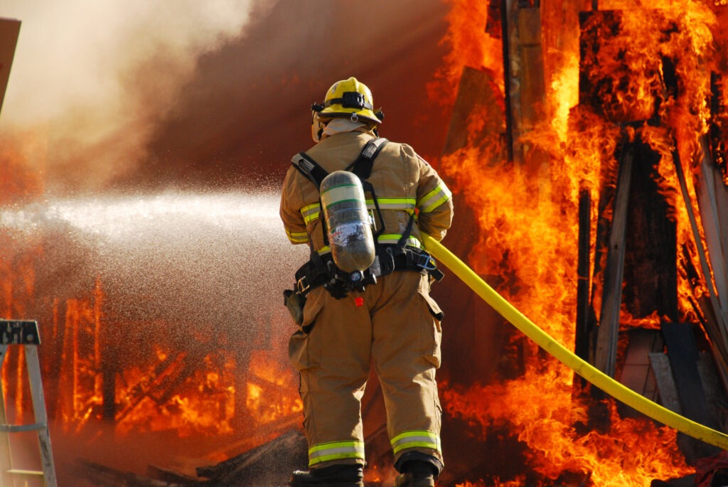 Firefighter hosing down the McKinney wildfire as it blazes across a forest