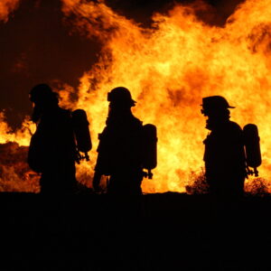 Three fireman sillhouettes in front of a blazing fire.