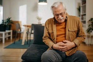 Latino worker clutching his stomach after experiencing symptoms of Parkinson's.
