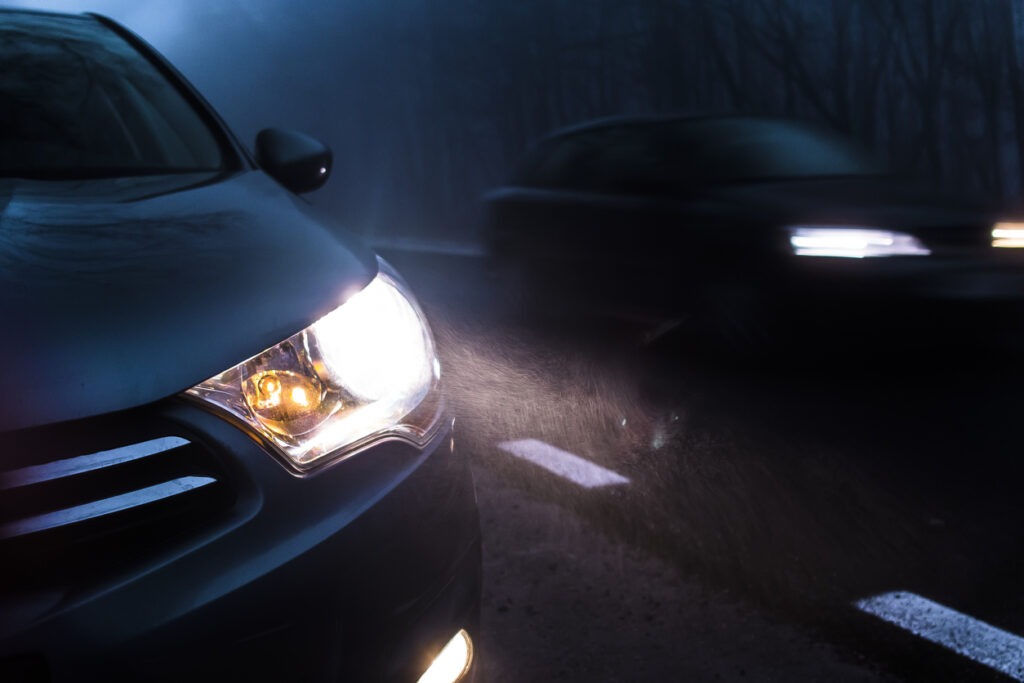 Cars driving with their headlights on at night.