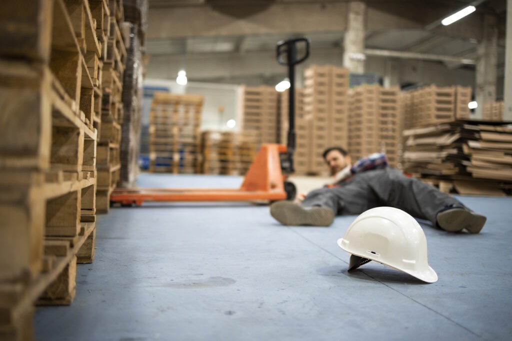 a worker fallen on the ground in a warehouse after a slip and fall accident.