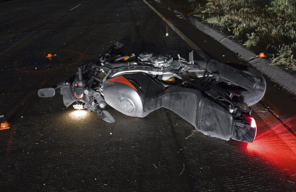 A motorcycle on the side of the road at night after a crash.