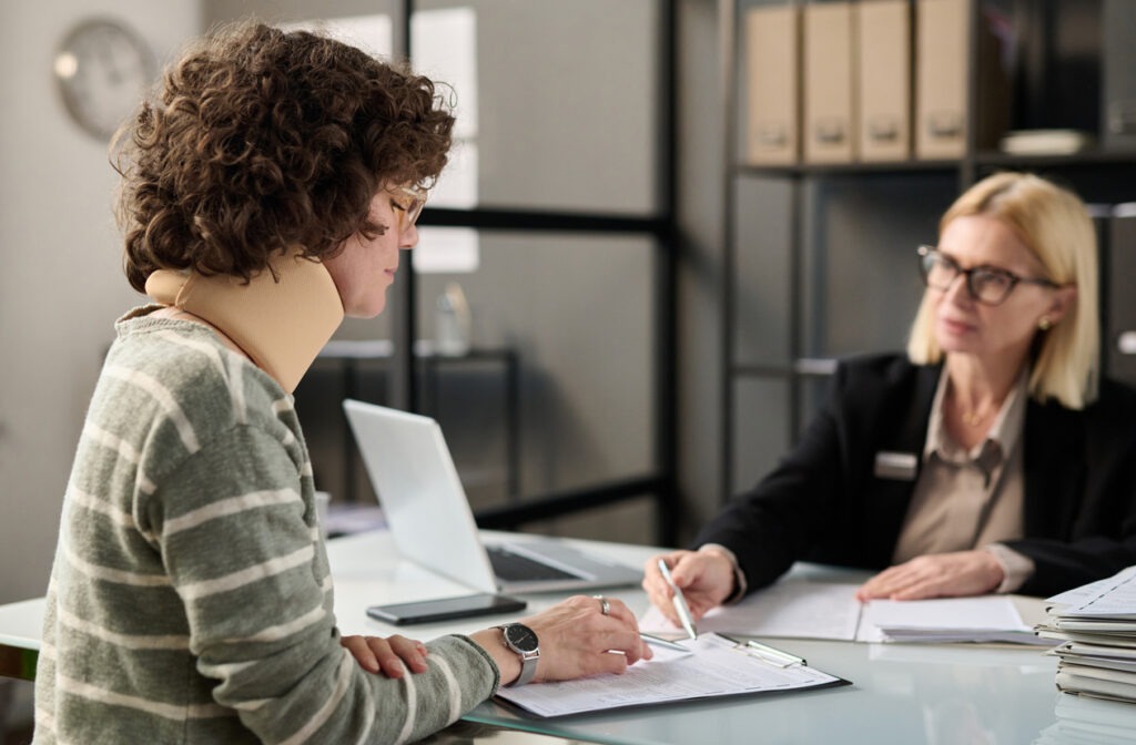 A woman in a neck brace discussing her case with a lawyer.