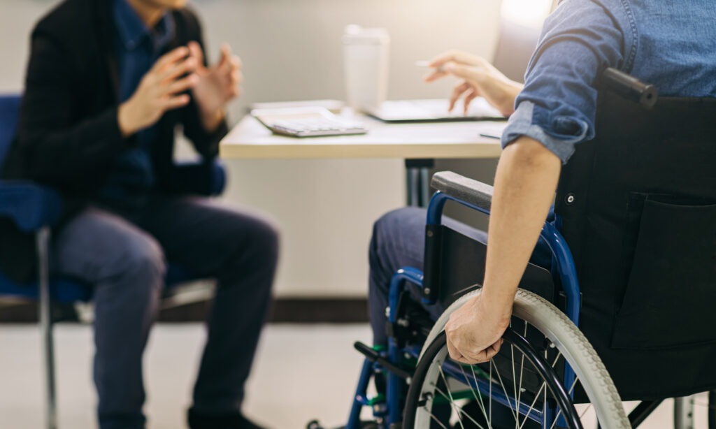 A man in a wheelchair discussing his condition with a lawyer