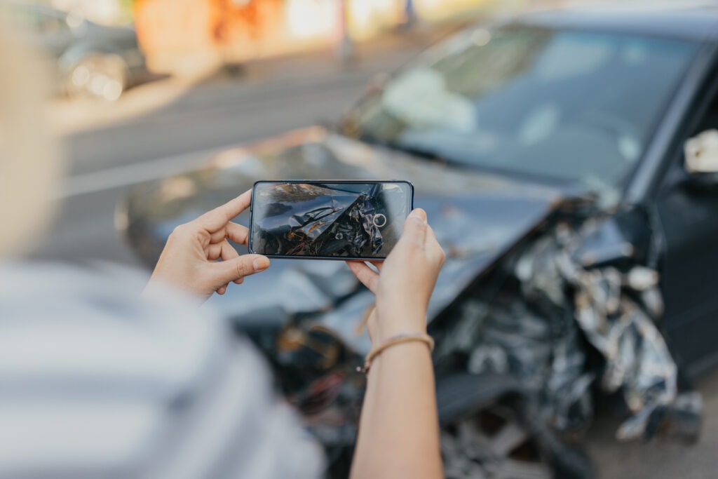 Close up of hands photographing damaged car