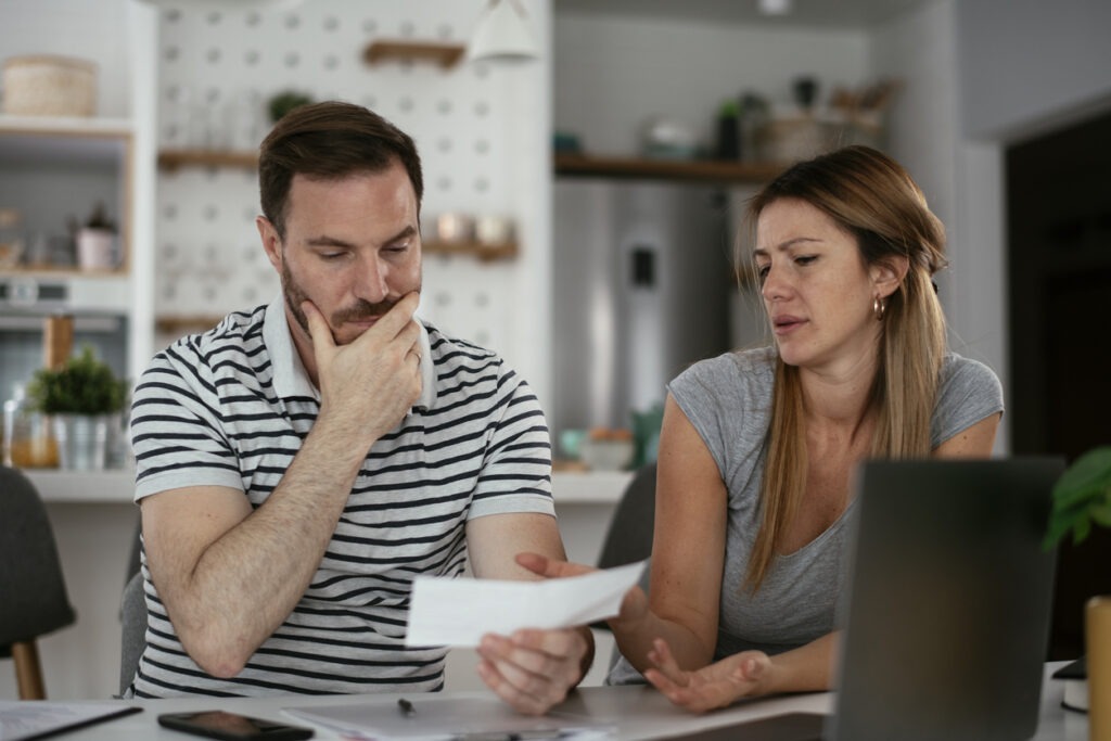 Pensive couple reviewing the value of an insurance check at home