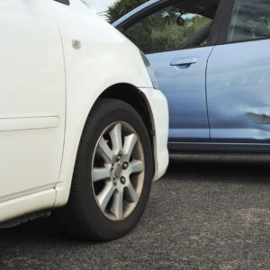 White and blue cars stopped in a minor accident with a dent on the blue car's back door.