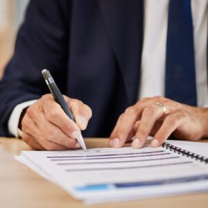 A lawyer in a navy suit taking notes on their desk.